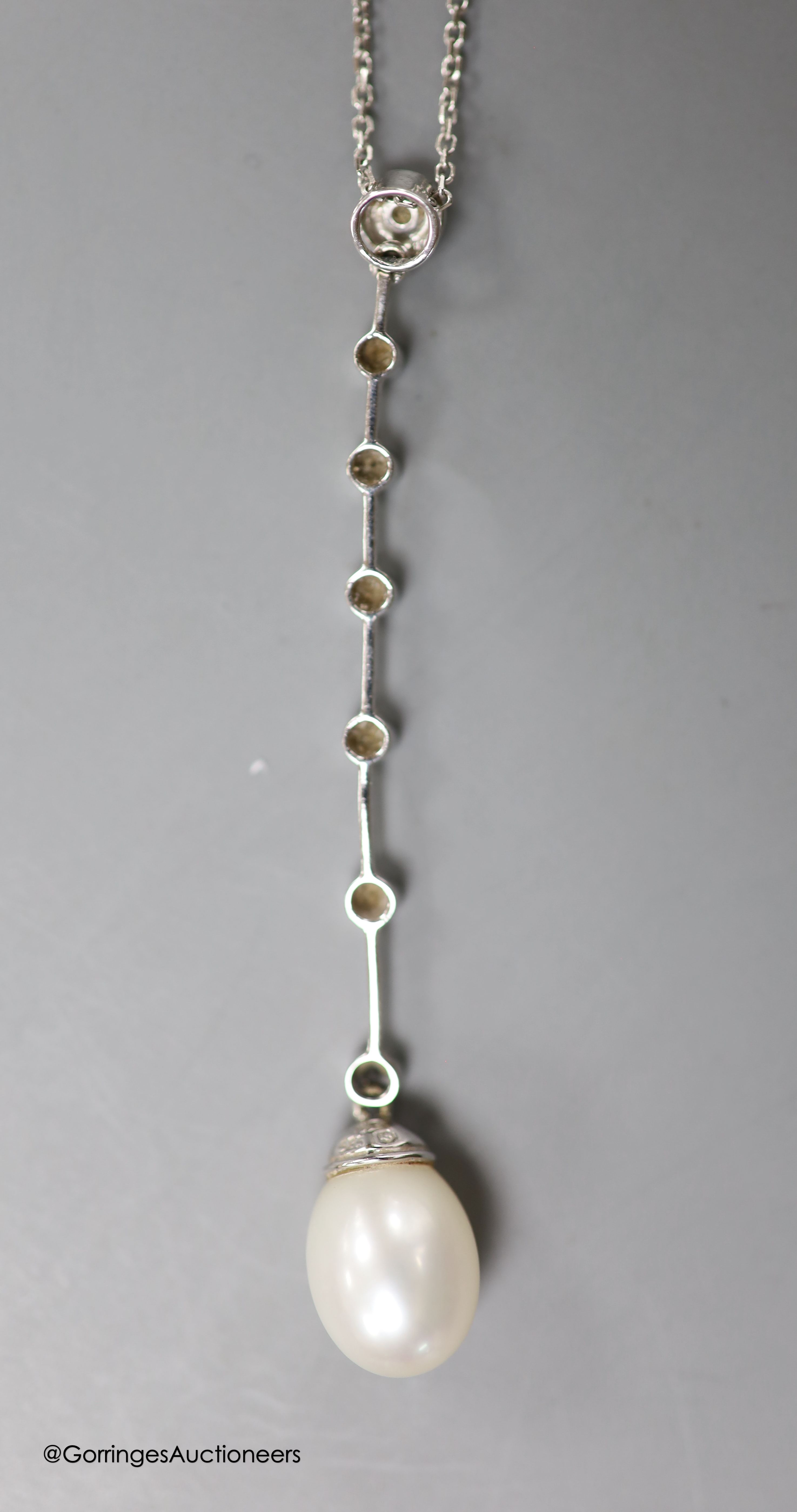 A modern white metal (stamped 14kt), cultured pearl and seven stone diamond chip set drop line pendant necklace, pendant 6cm, chain, 45cm, gross weight 4.1 grams.